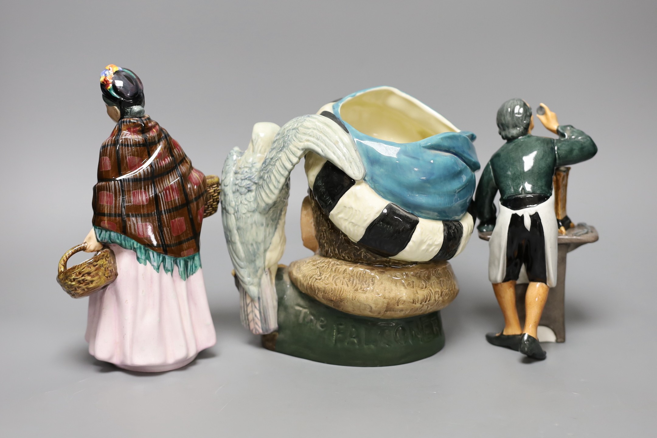 Two Royal Doulton figures, ‘The Clockmaker HN2279’ and ‘The Orange Lady HN1759’ together with a character jug ‘The Falconer D6533’